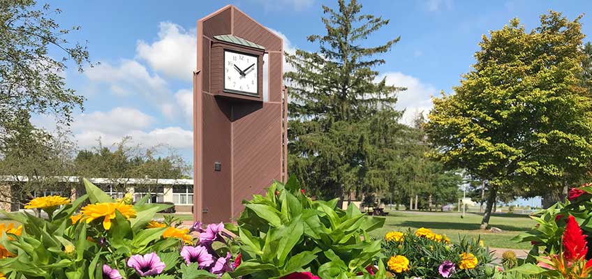 Campus clocktower in background with summer flowers in foreground