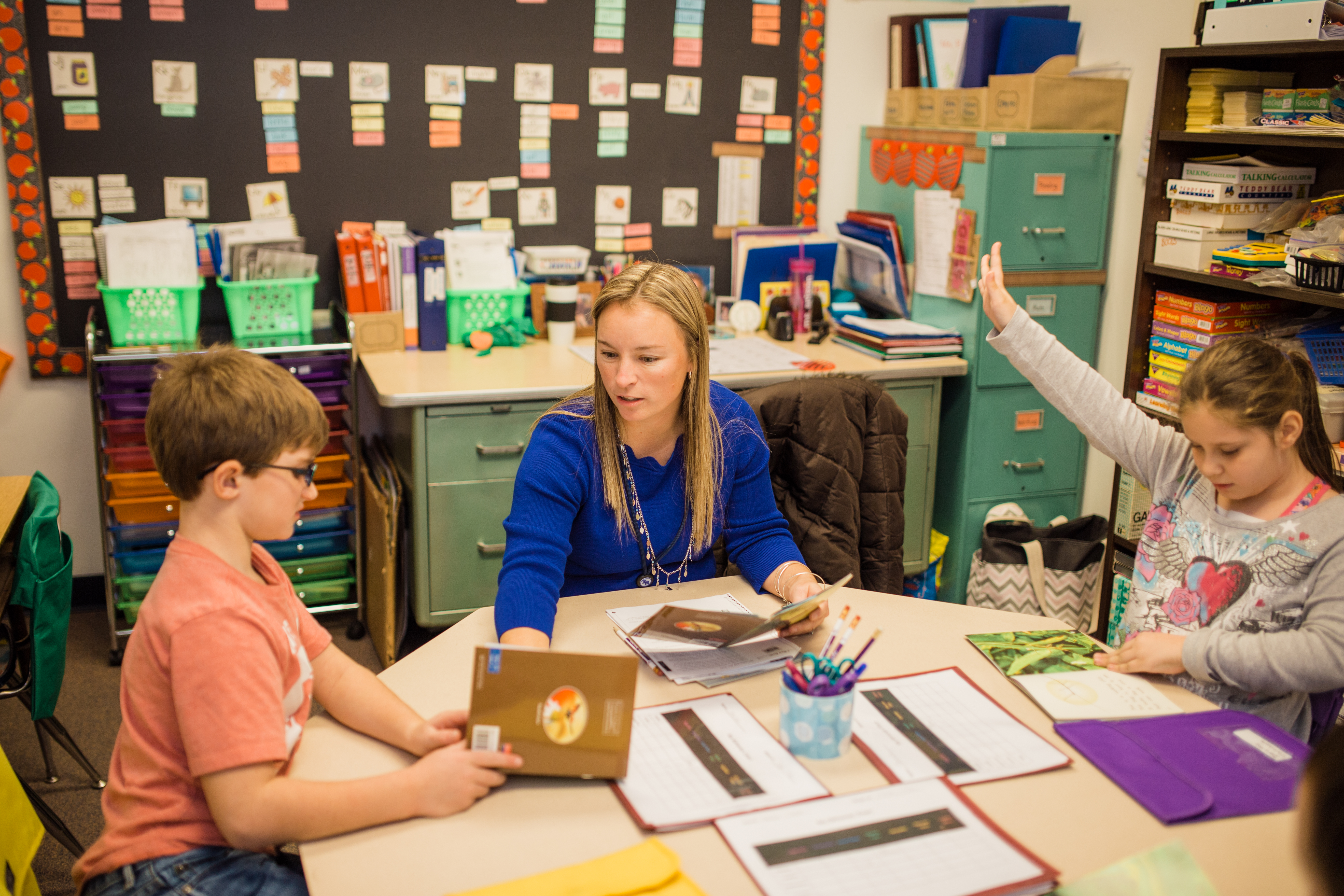 Teacher sitting at table with two students