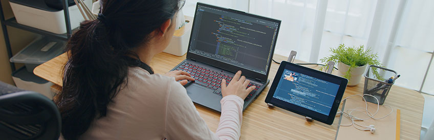 Female computer programmer writing code on laptop