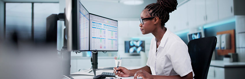 Healthcare Professional Using Spreadsheet For Billing Codes On Desktop