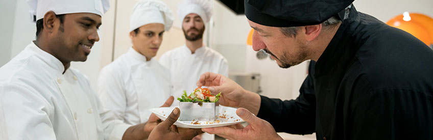 Head chef checking a salad that the sous chef just made