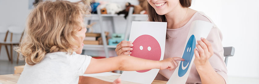 Smiling counselor holding pictures during meeting with young patient