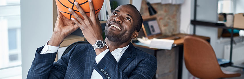 Joyful Businessman in suit holding orange basketball with smile. 