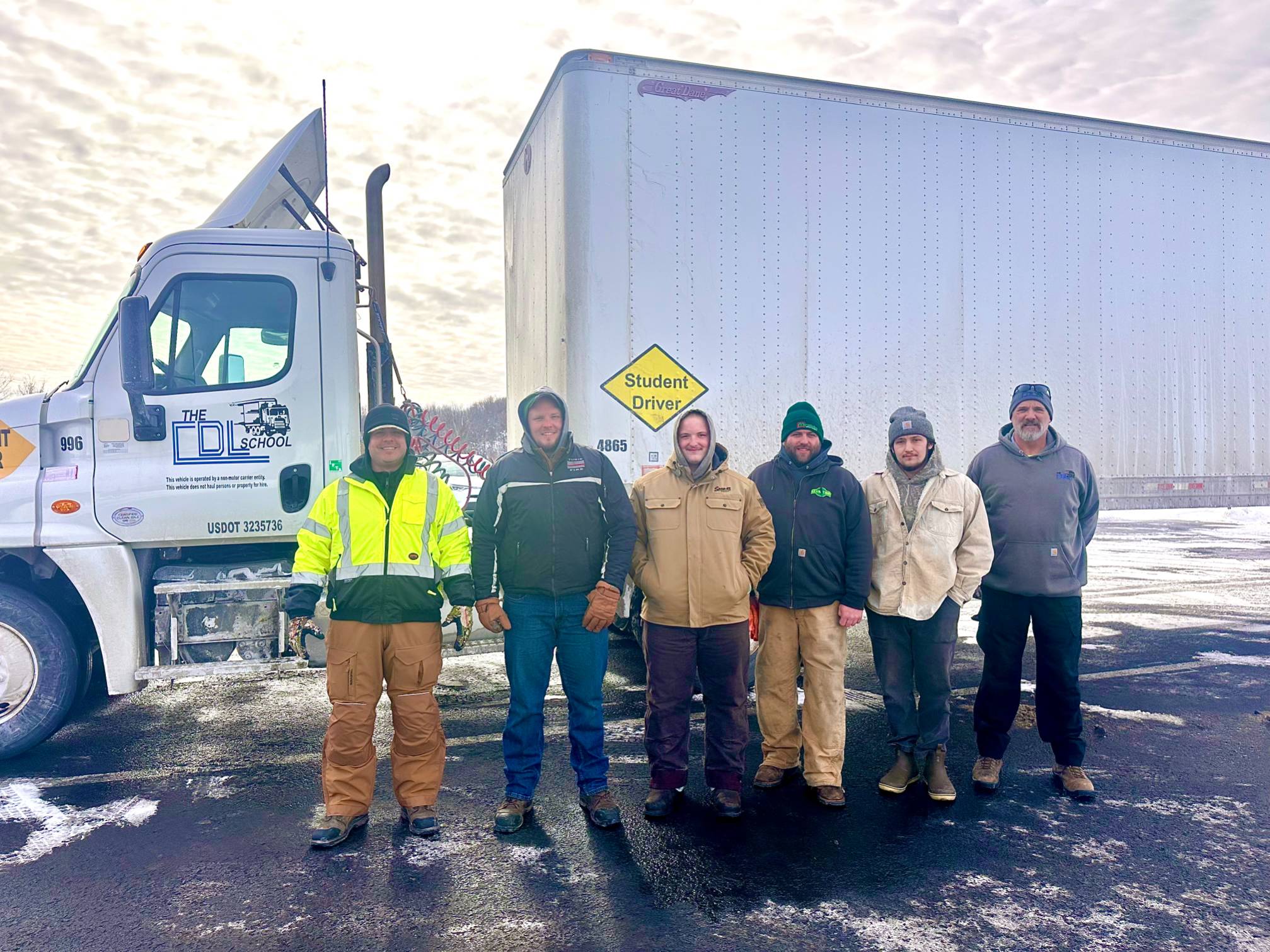 Six men standing in front of a tractor trailer.
