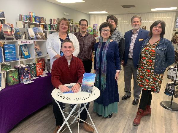 Dylan Kernehan posing with members of the JCC community and owner of the The Little Bookstore