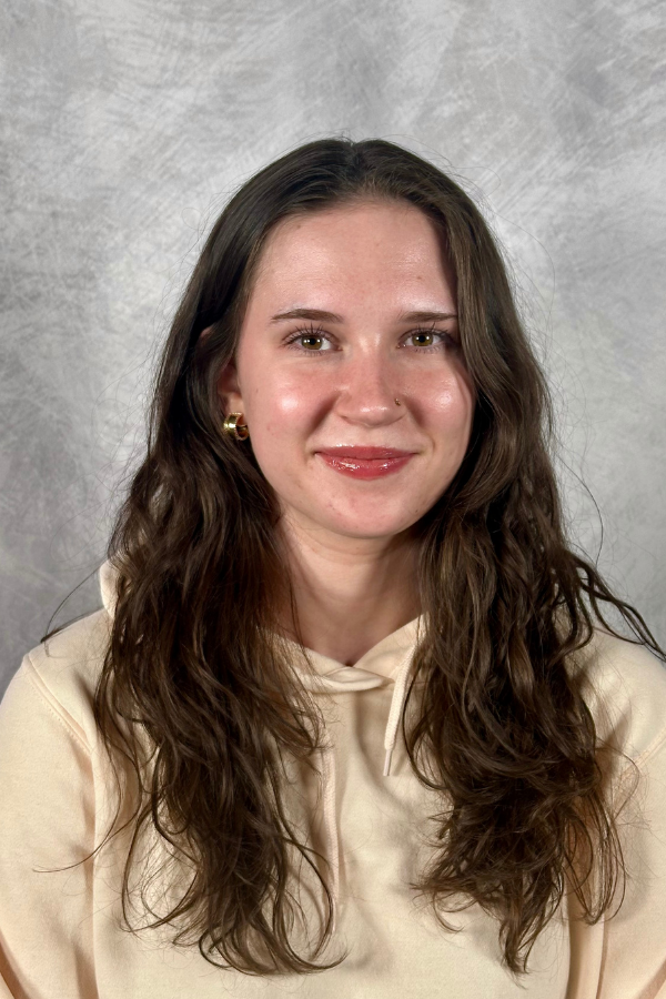 Photo of a woman wearing a cream colored sweatshirt posting for a picture