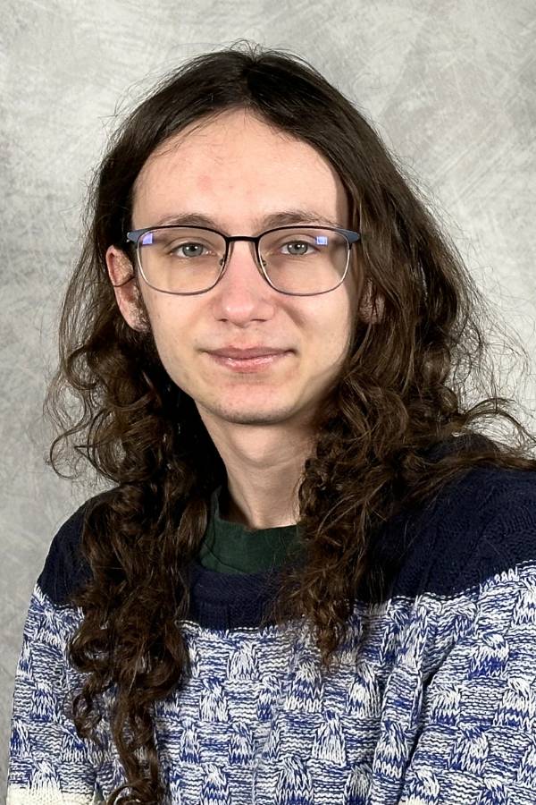 Image of a person wearing a tri-color blue sweatshirt posing for a photo