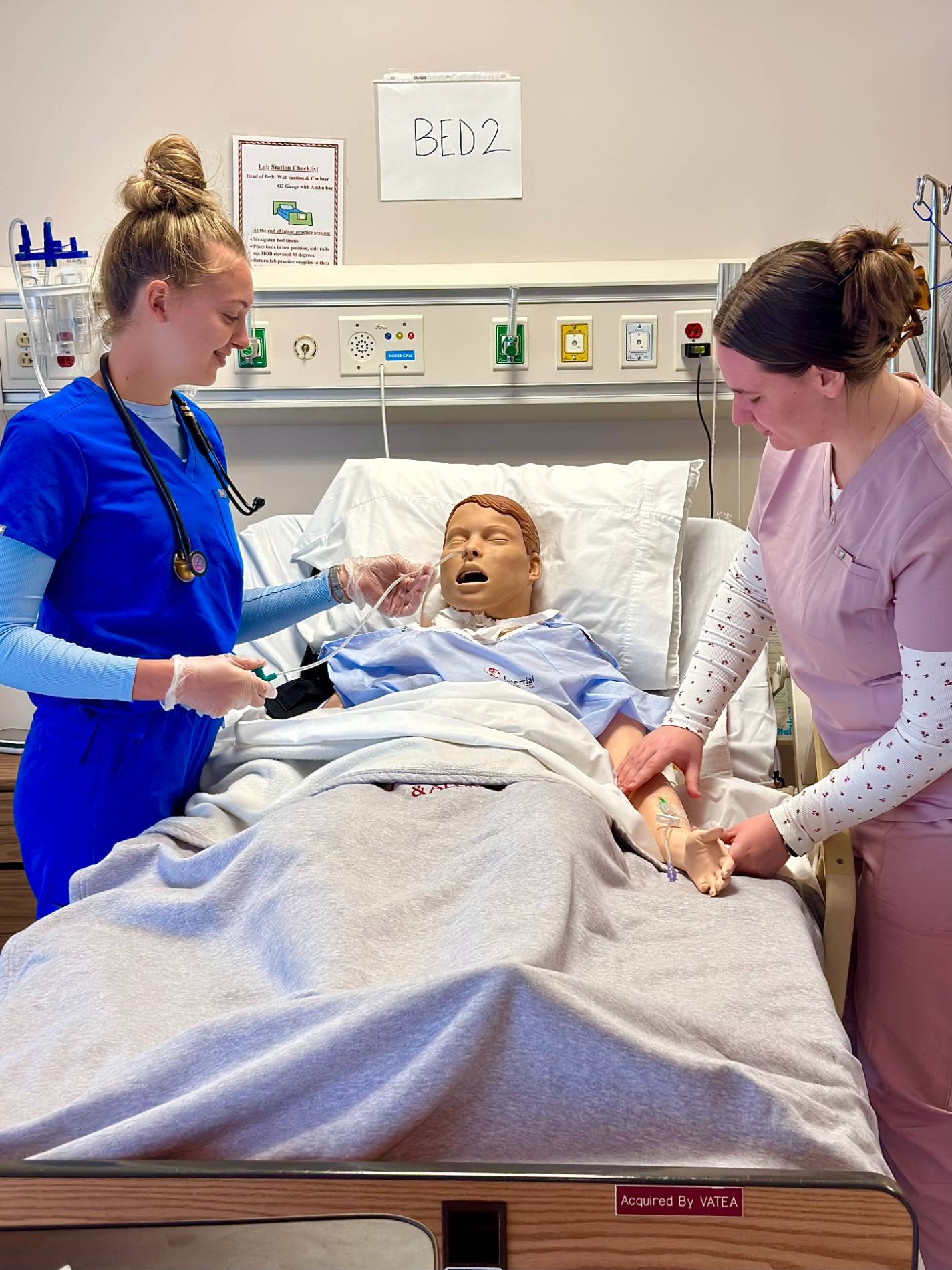 Image of two nursing students working on a mannequin in the nursing simulation lab